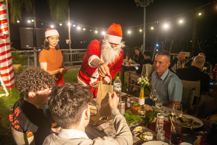 Santa hands out gifts on Christmas Eve from the Coco Casa Collection at Coco Casa in Hoi An, Vietnam